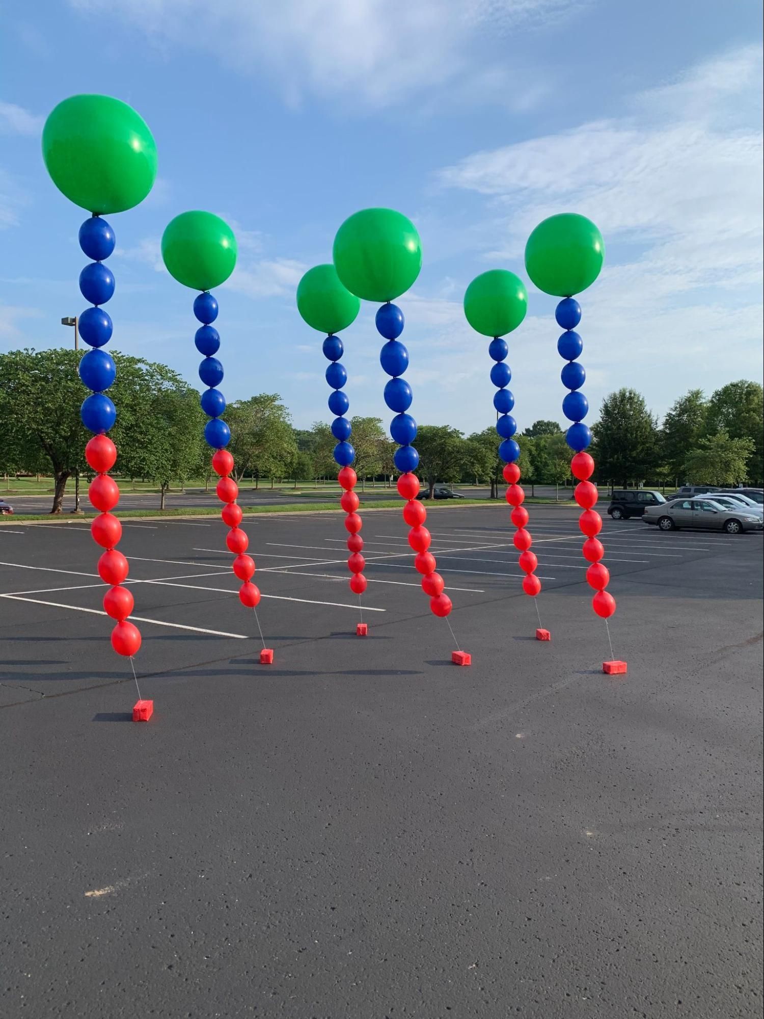 A bunch of balloons hanging from poles in a parking lot