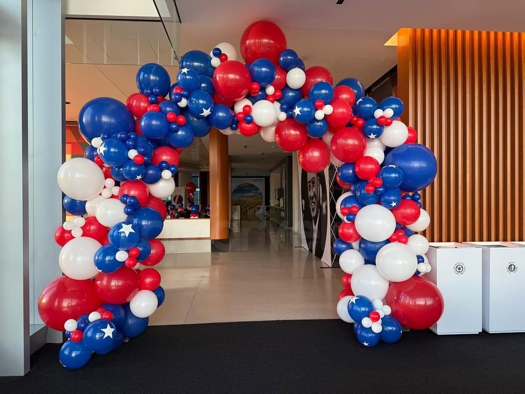 A red white and blue balloon arch in a hallway
