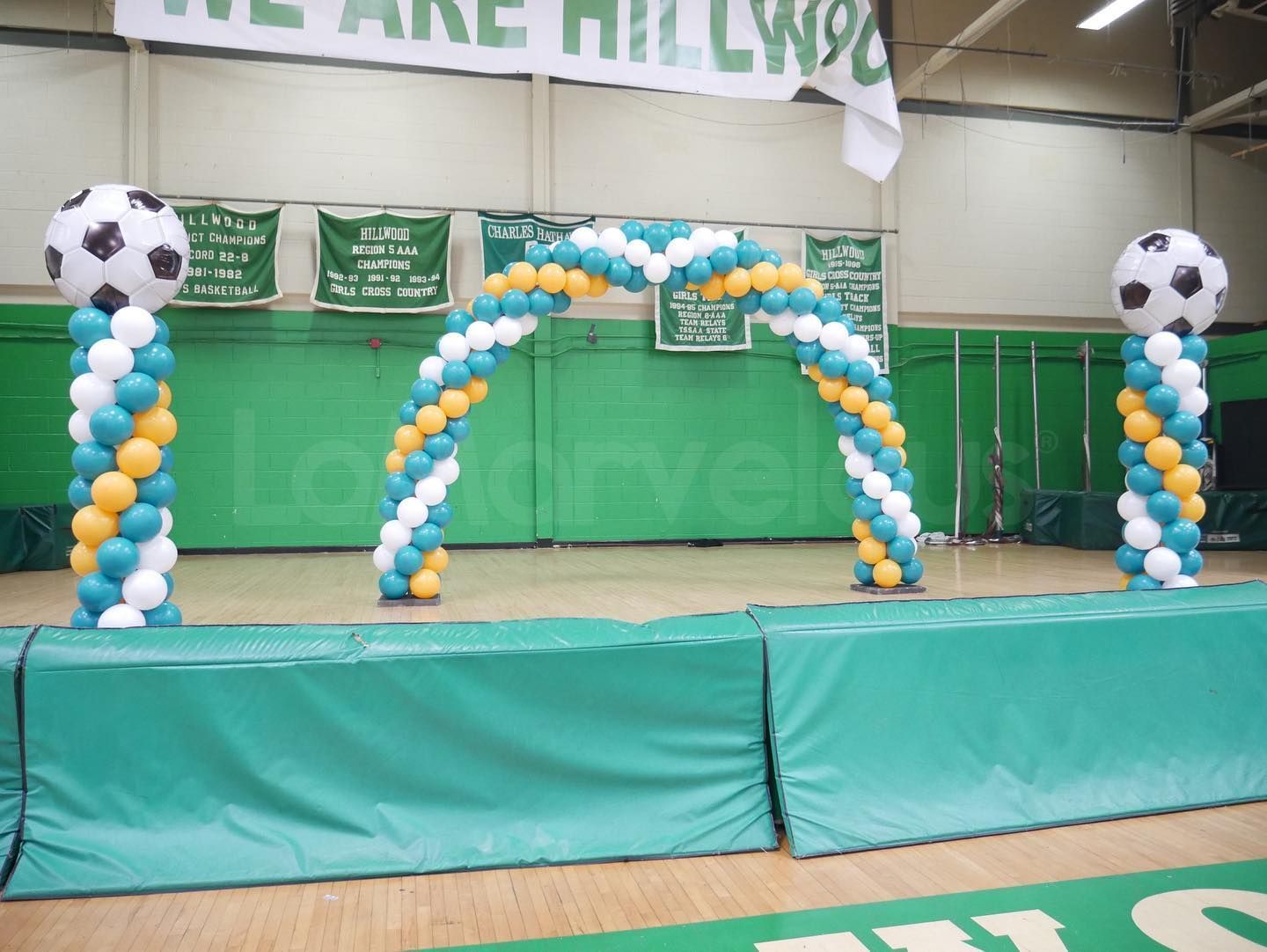 A stage decorated with blue and yellow balloons and soccer balls