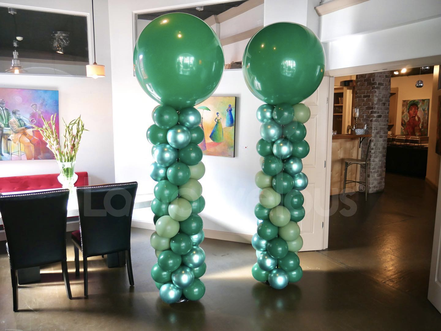 Two green balloons are stacked on top of each other in a room