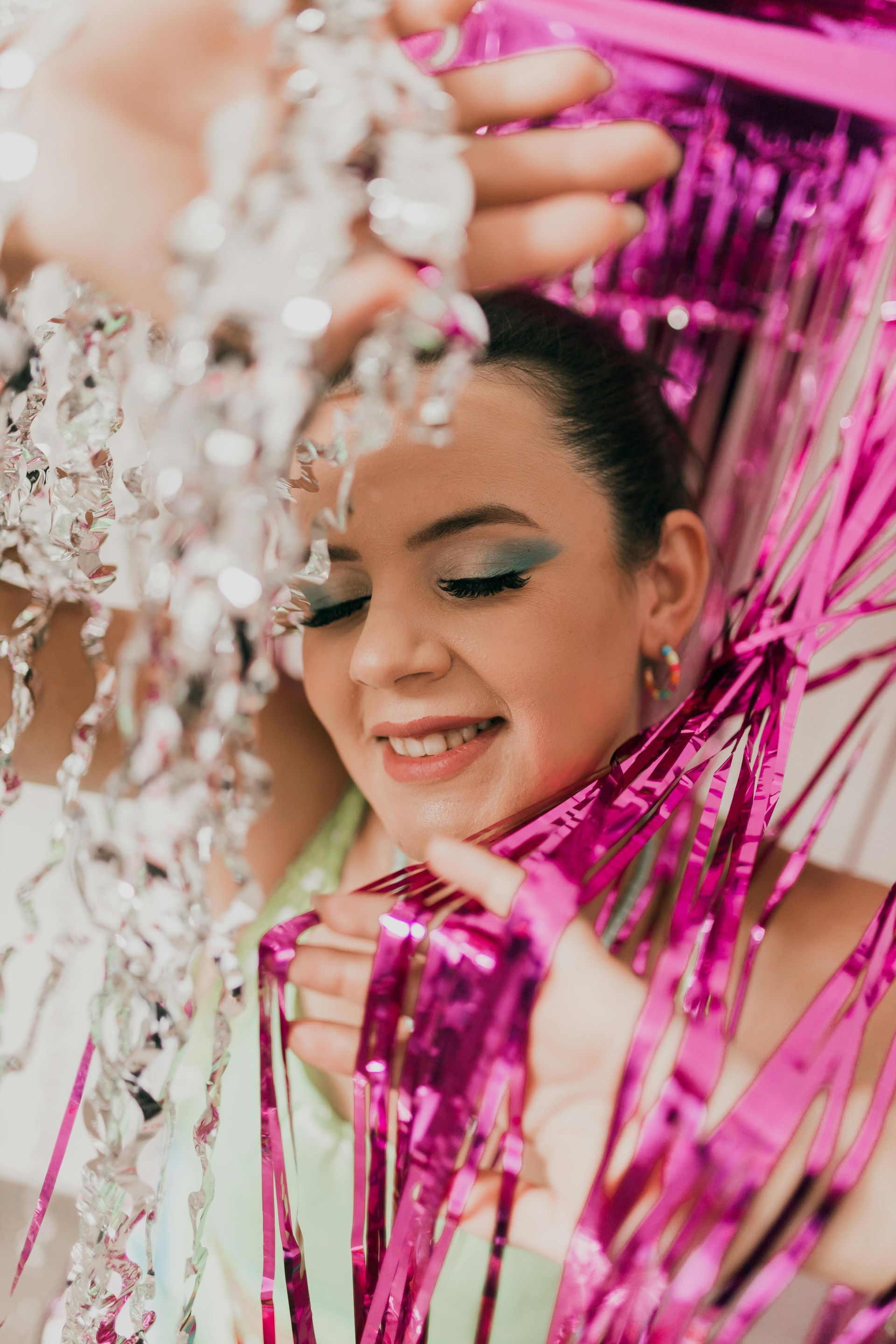 A woman is holding pink and silver tinsel in front of her face.