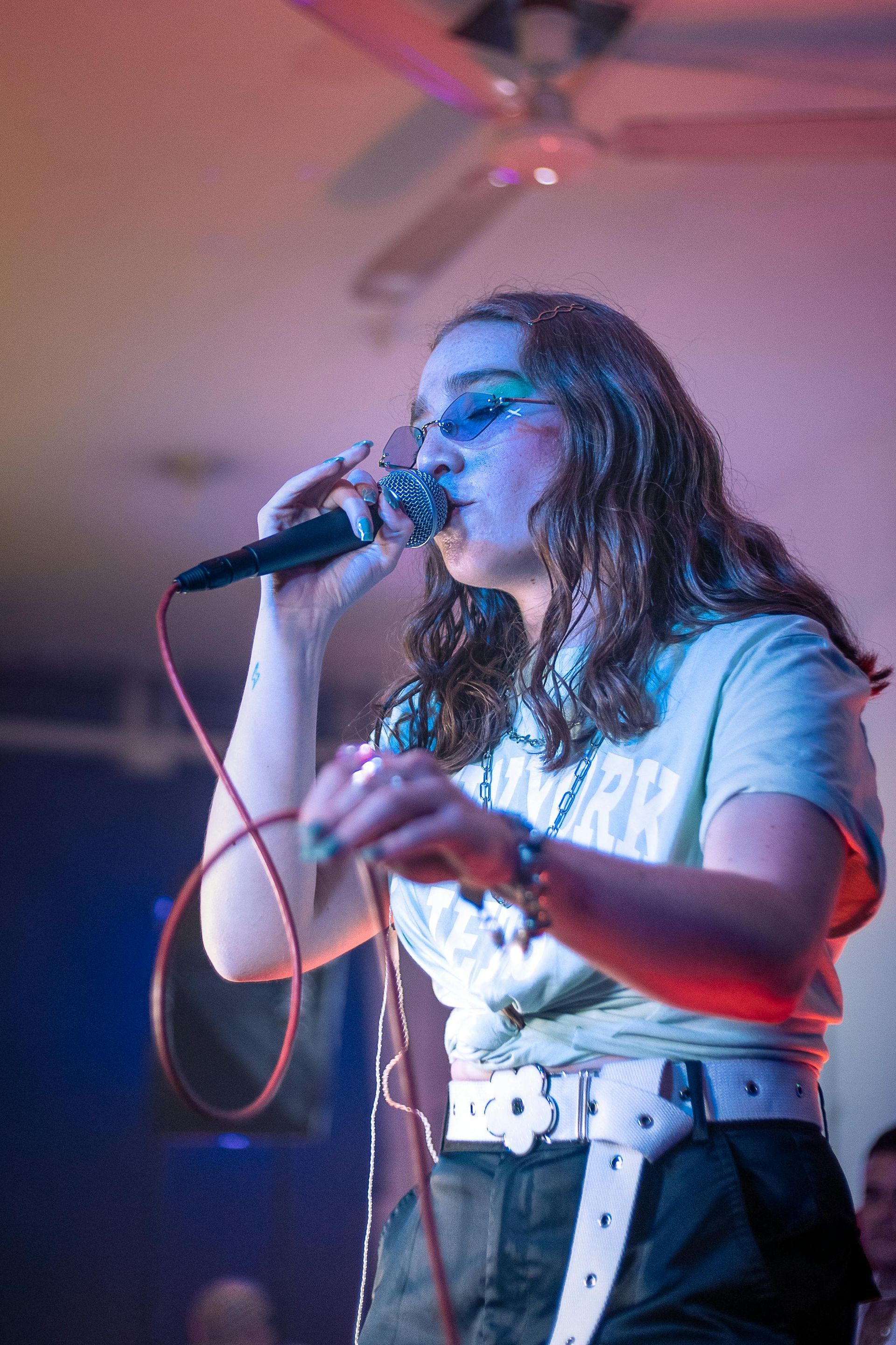 A woman is singing into a microphone on a stage.