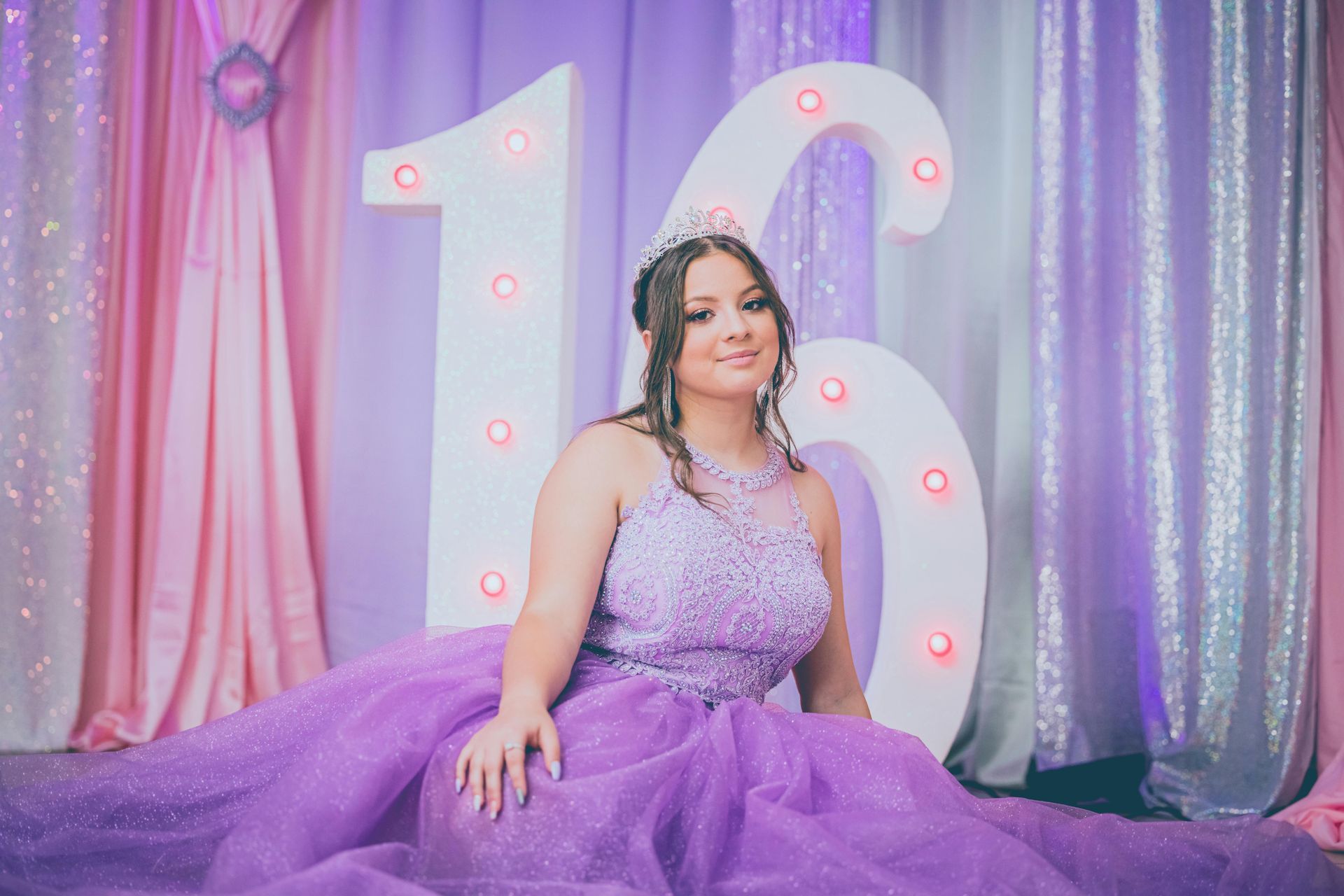 A woman in a purple dress is sitting in front of a large number 16.