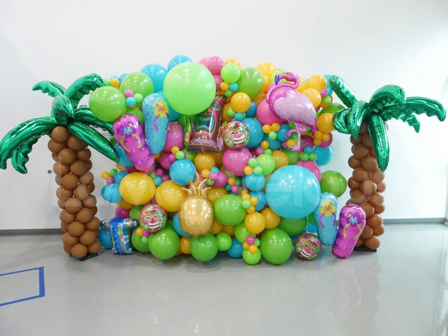 A wall of balloons with palm trees in the background