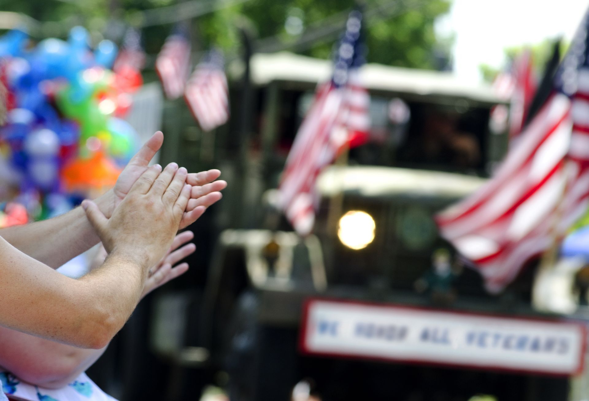 clapping hands at a veteran celebration with balloons and flags