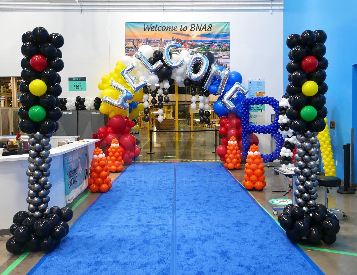 A blue carpet is surrounded by balloons and a sign that says welcome