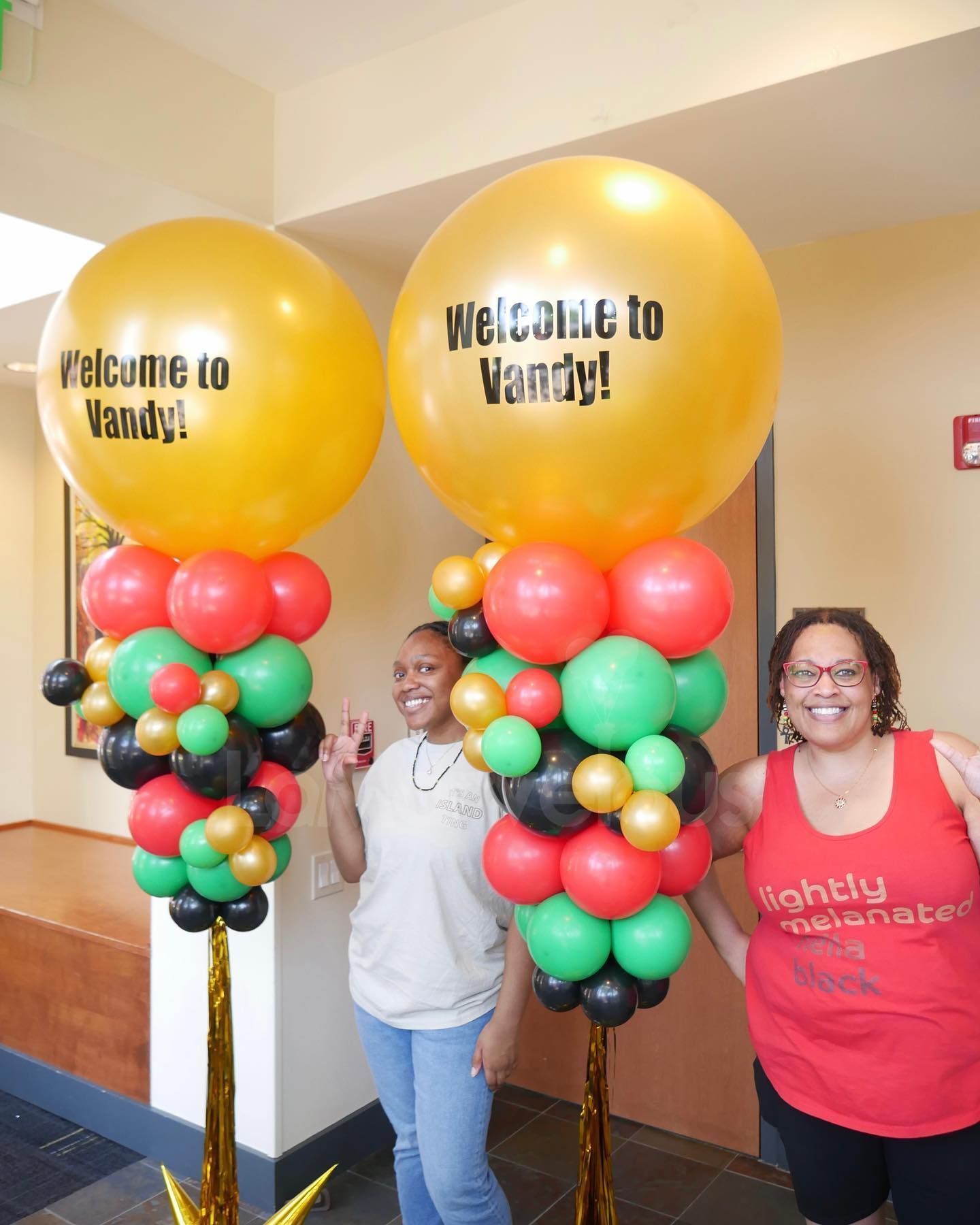 Two women standing next to balloons that say welcome to vandy