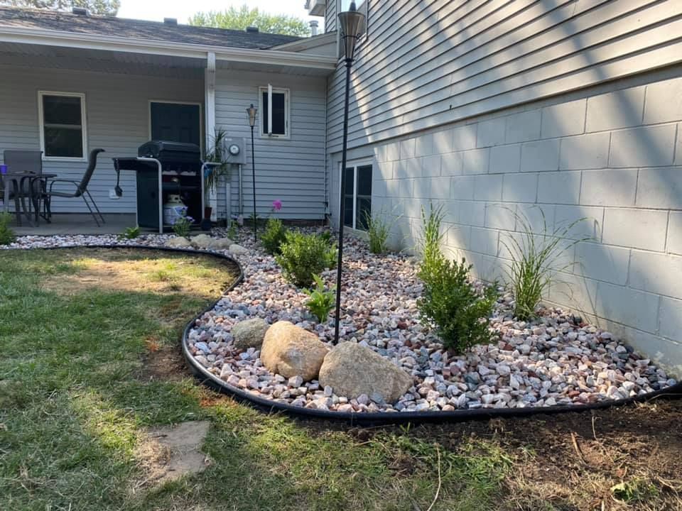 A garden with rocks and plants in front of a house.
