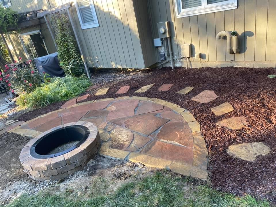 A fire pit is sitting in the middle of a patio next to a house.