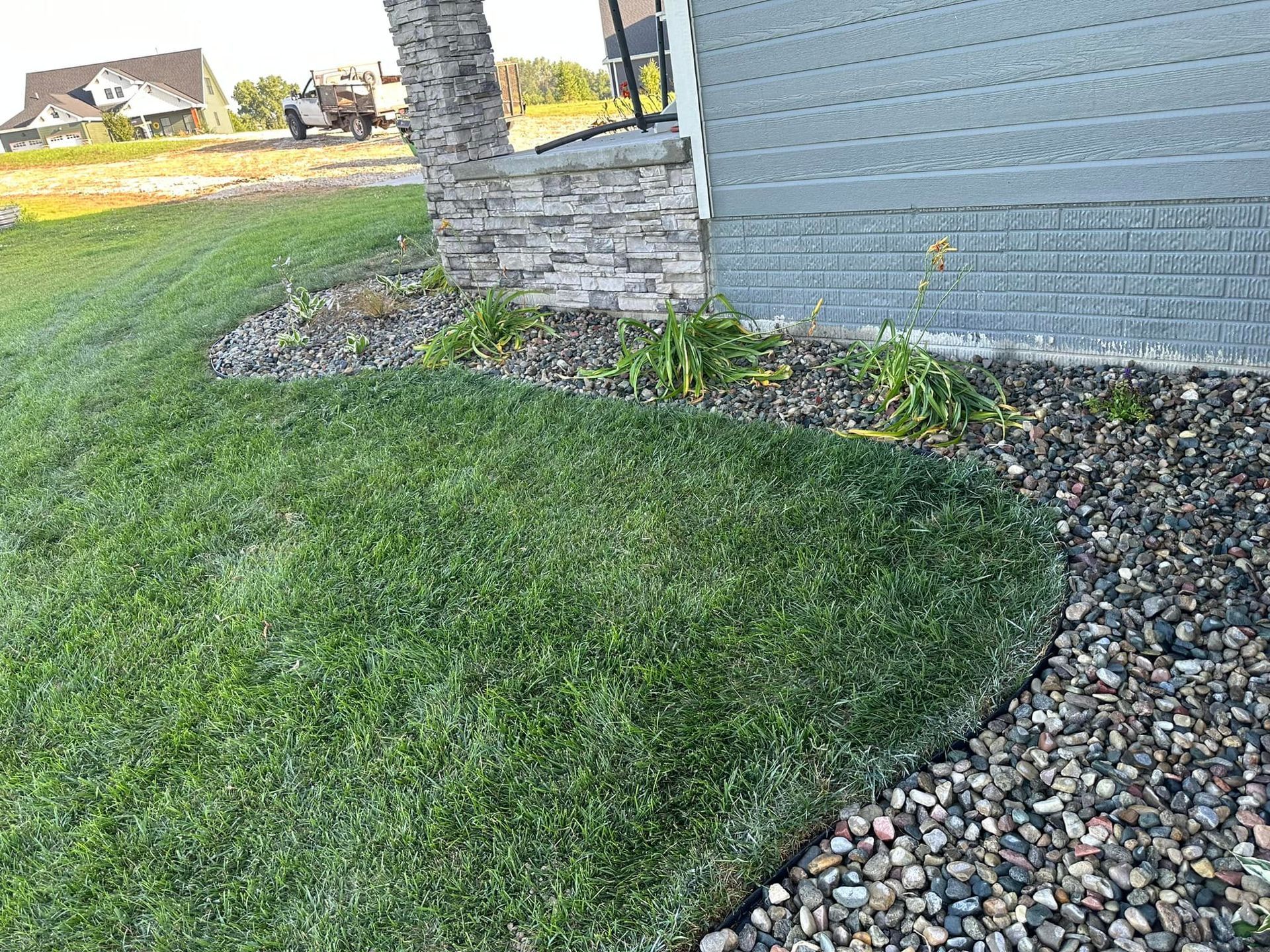 A house with a lot of grass and rocks in front of it.