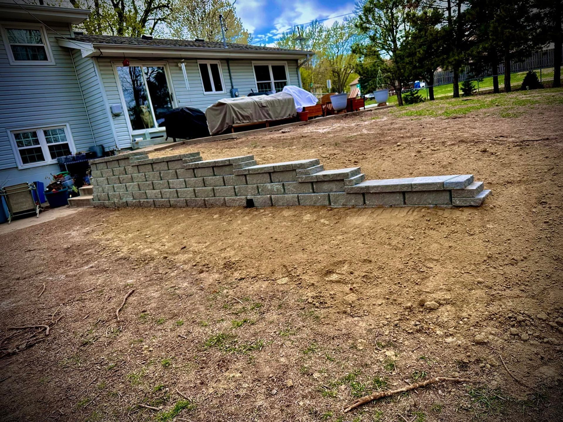 A brick wall is being built in the backyard of a house.