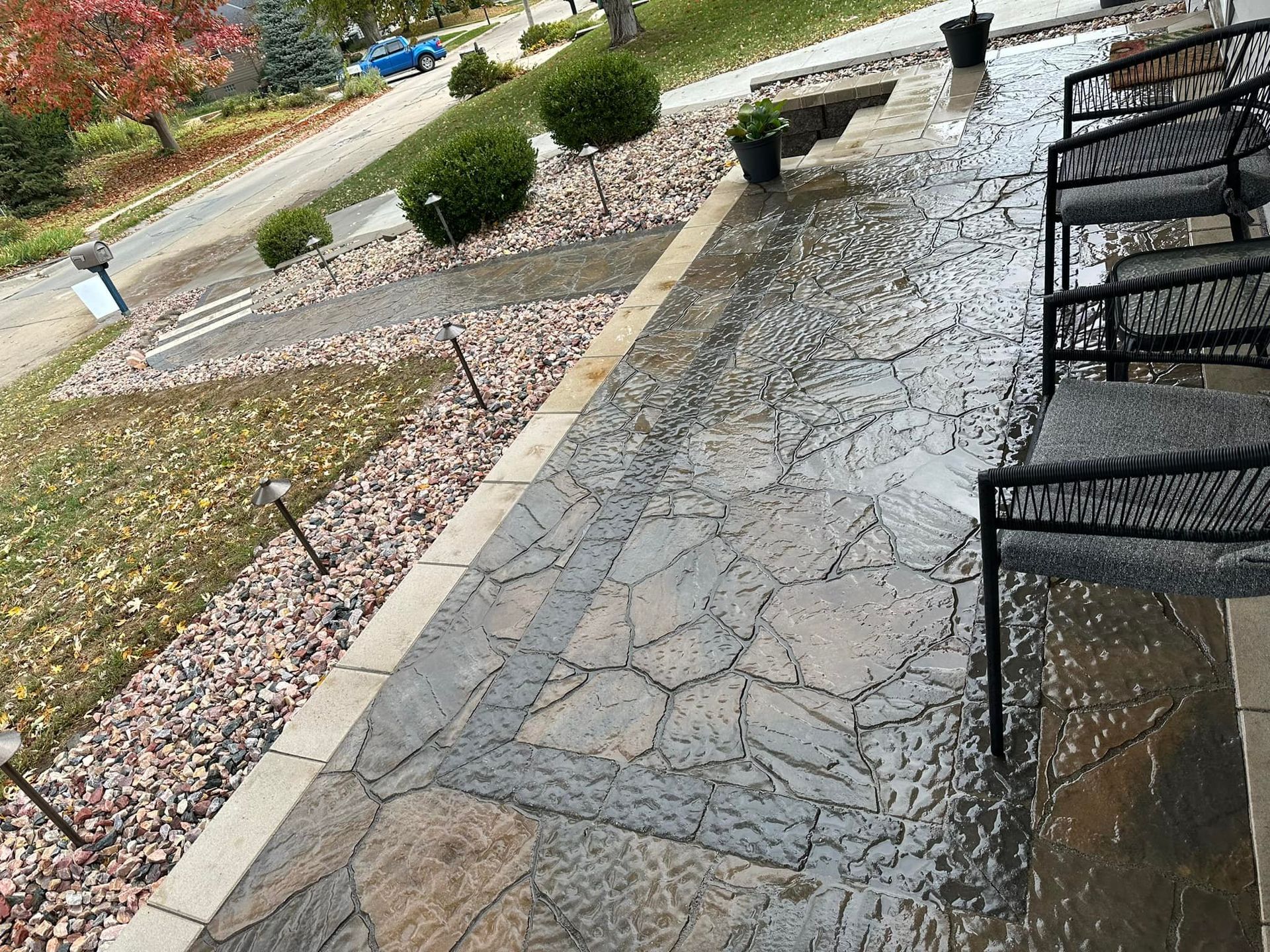 A patio with chairs and a bench in the rain.