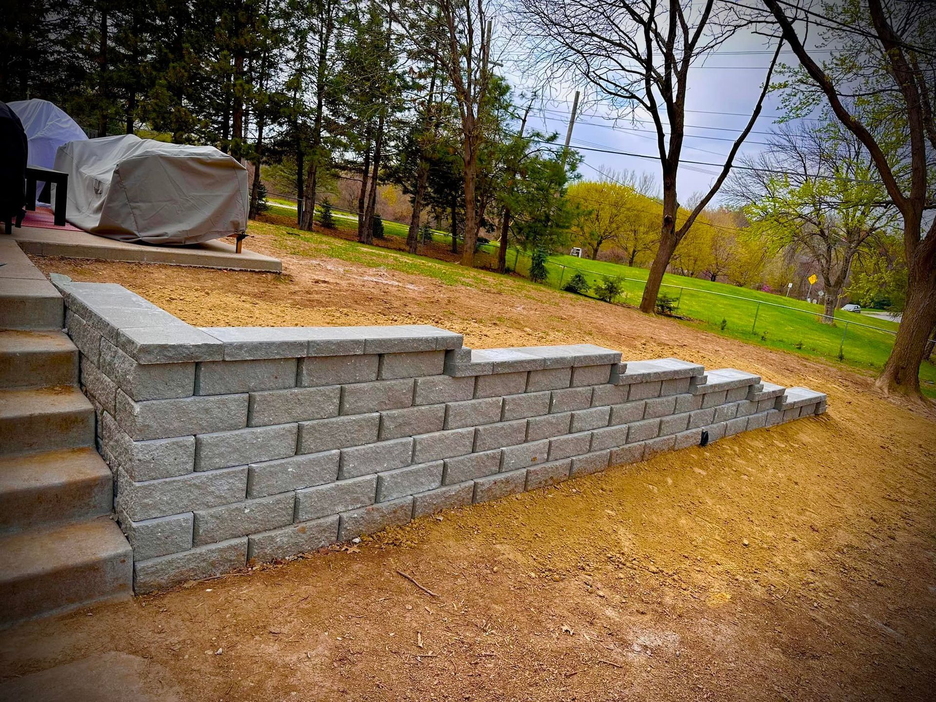 A brick wall with stairs leading up to it in a backyard.