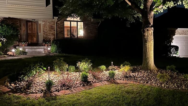 The front yard of a house is lit up at night.