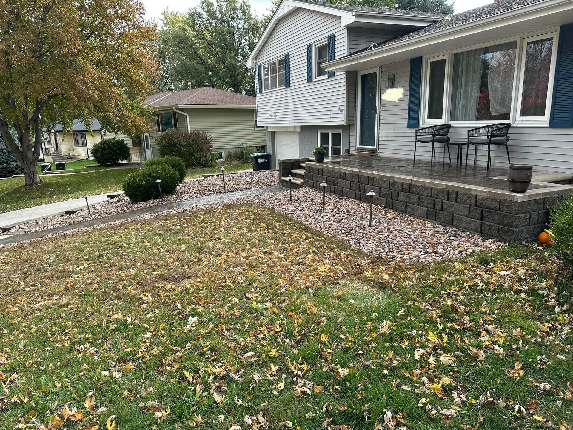 A house with a large lawn and a porch covered in leaves.