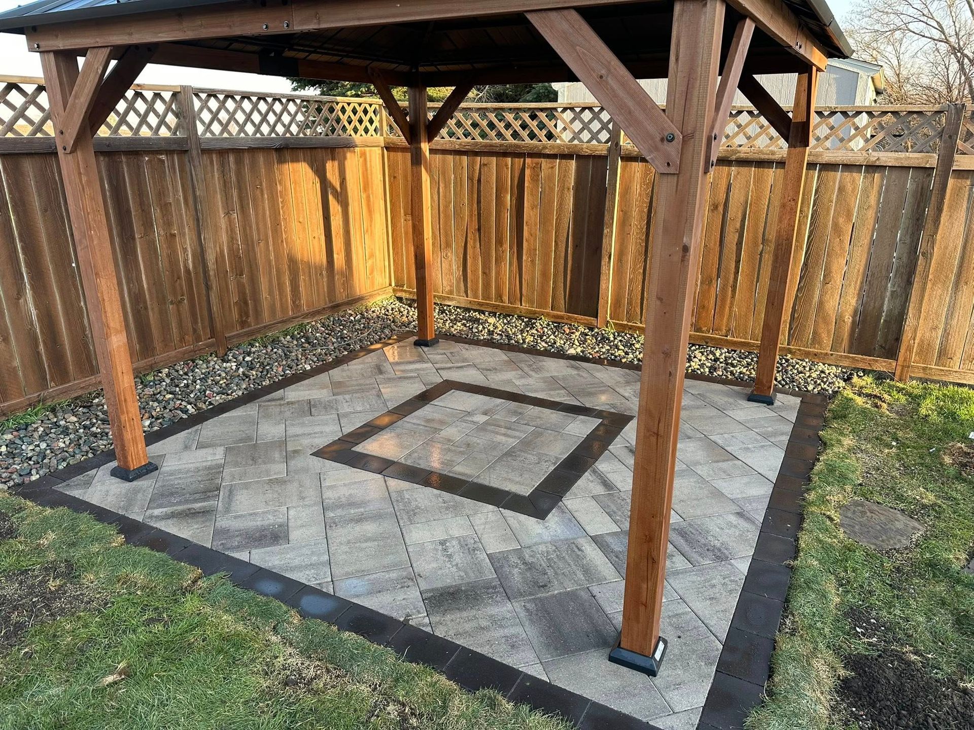 A wooden gazebo is sitting in the middle of a backyard next to a wooden fence.