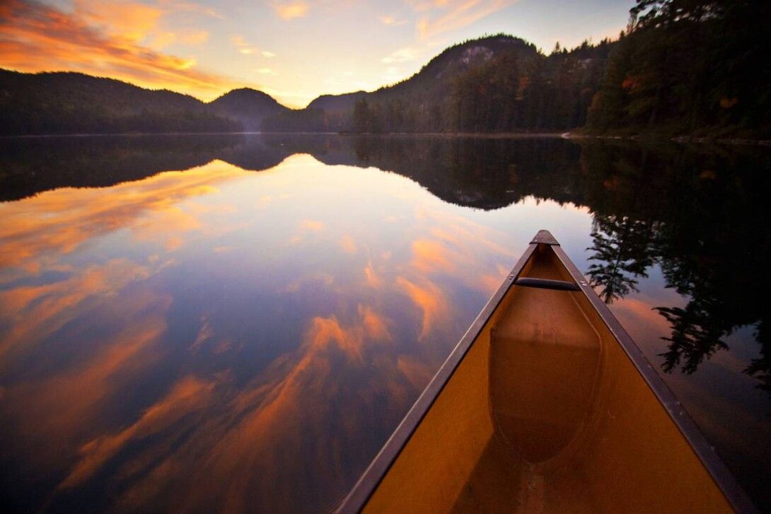 Un canoë flotte sur un lac au coucher du soleil
