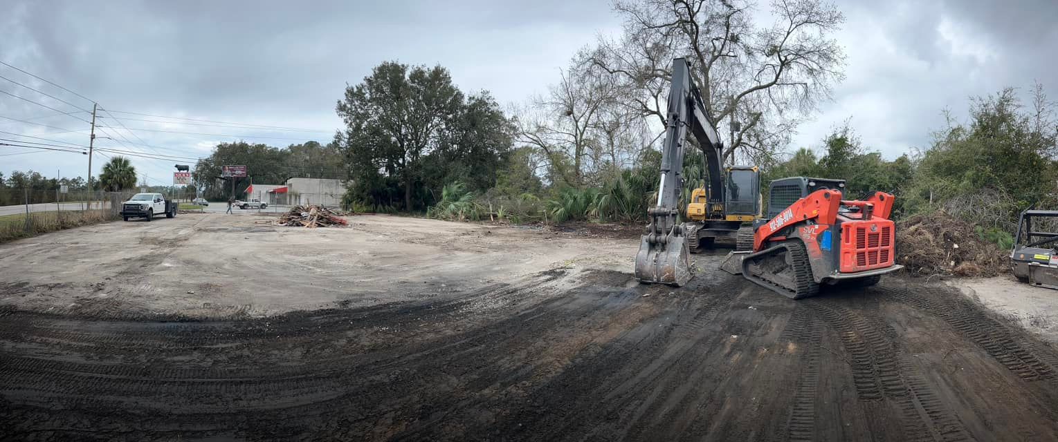A large orange excavator is working on a dirt road.
