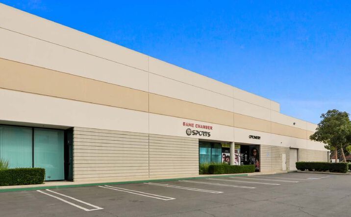 Exterior view of a commercial building with a blue sky. The building has various businesses.