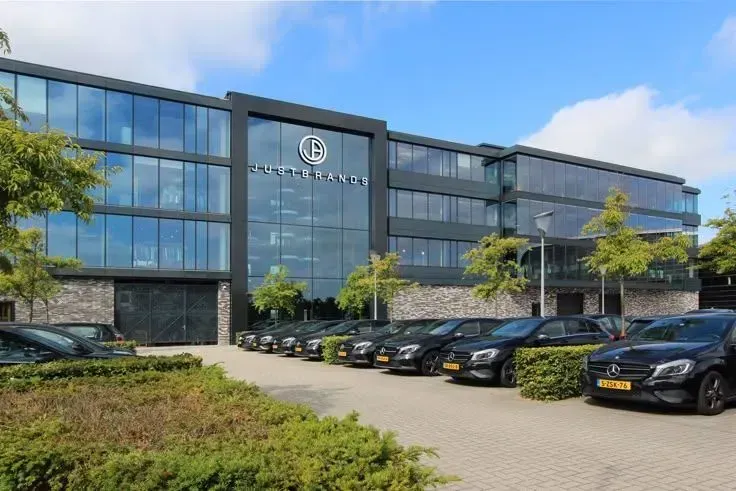 Black Mercedes cars parked in front of a modern, multi-story building with large windows and a company logo.