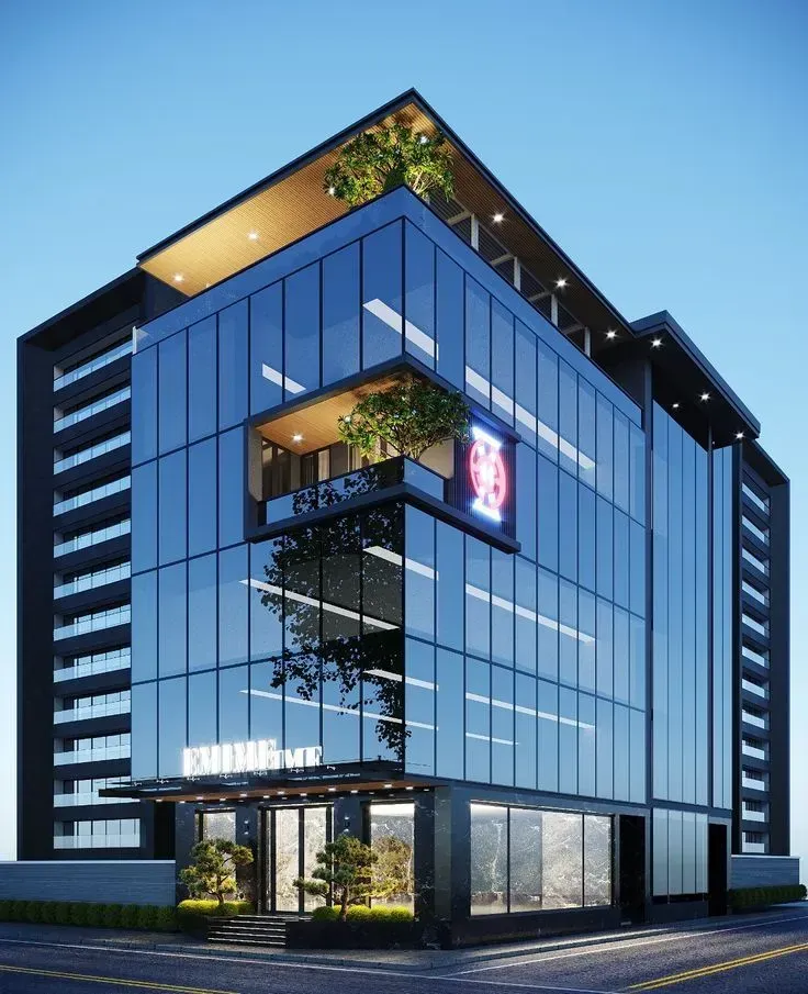 Modern glass office building with trees on balconies, under a blue sky.
