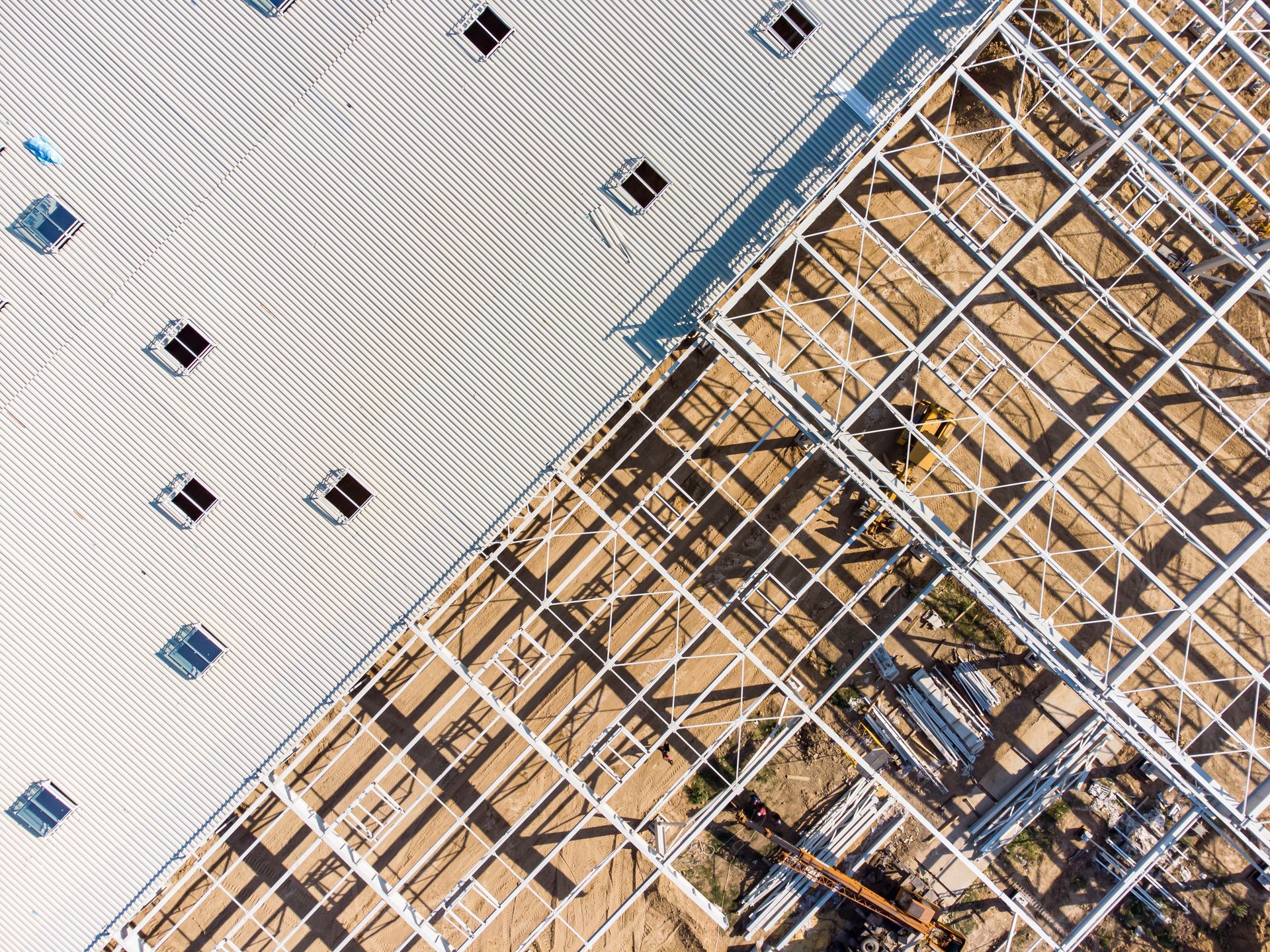 Overhead view of a building under construction; completed roof on the left, metal frame on the right.