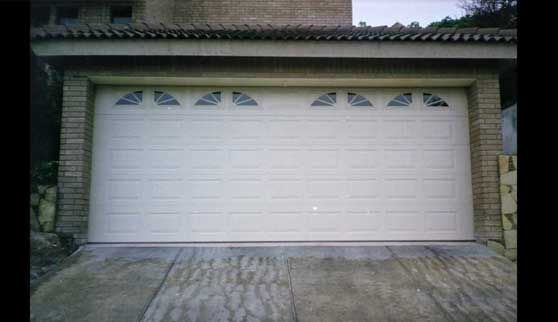 Una puerta de garaje blanca con un edificio de ladrillo al fondo