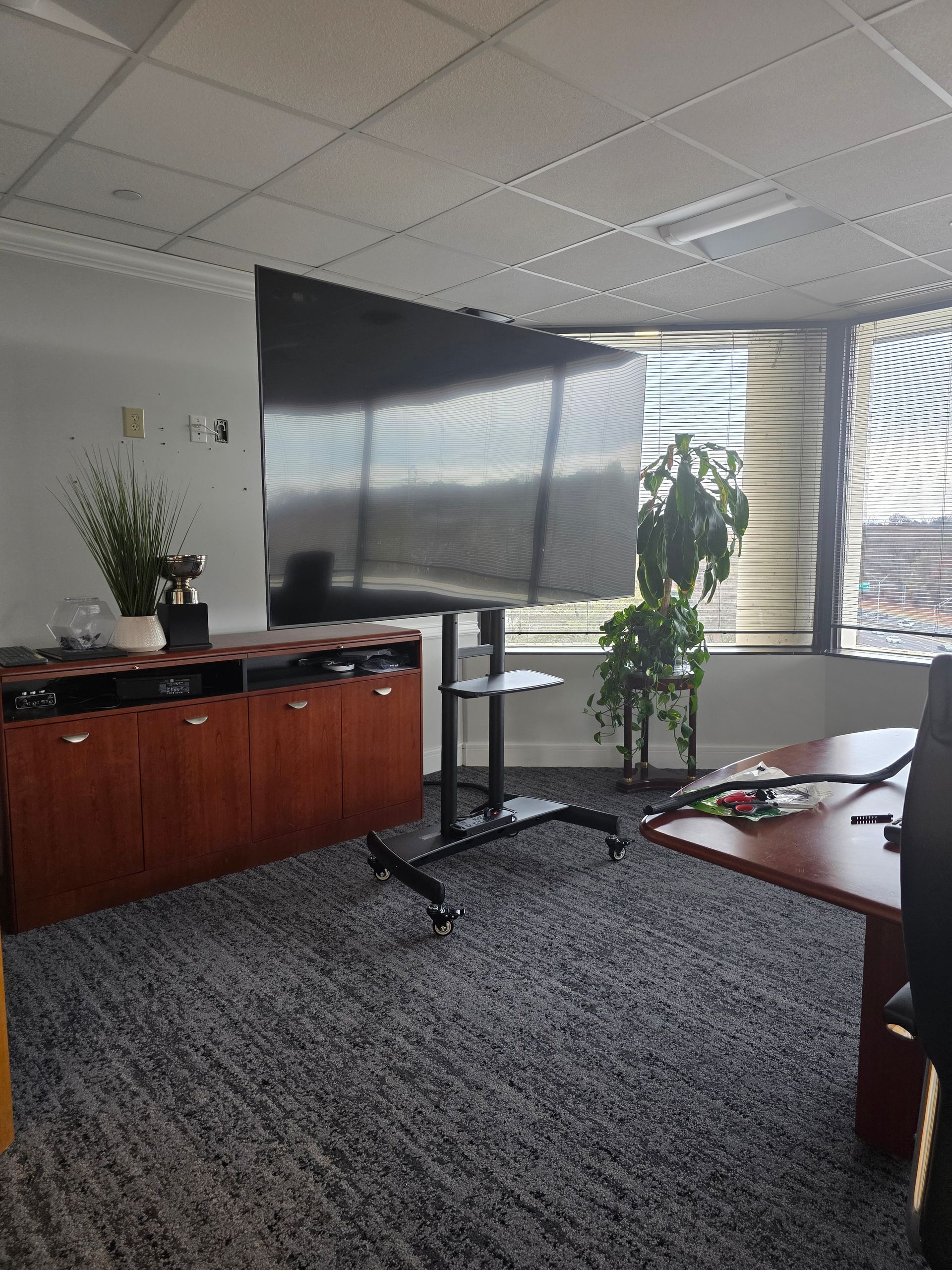 Woman in straw hat smiles, holding wine glass near a lake.