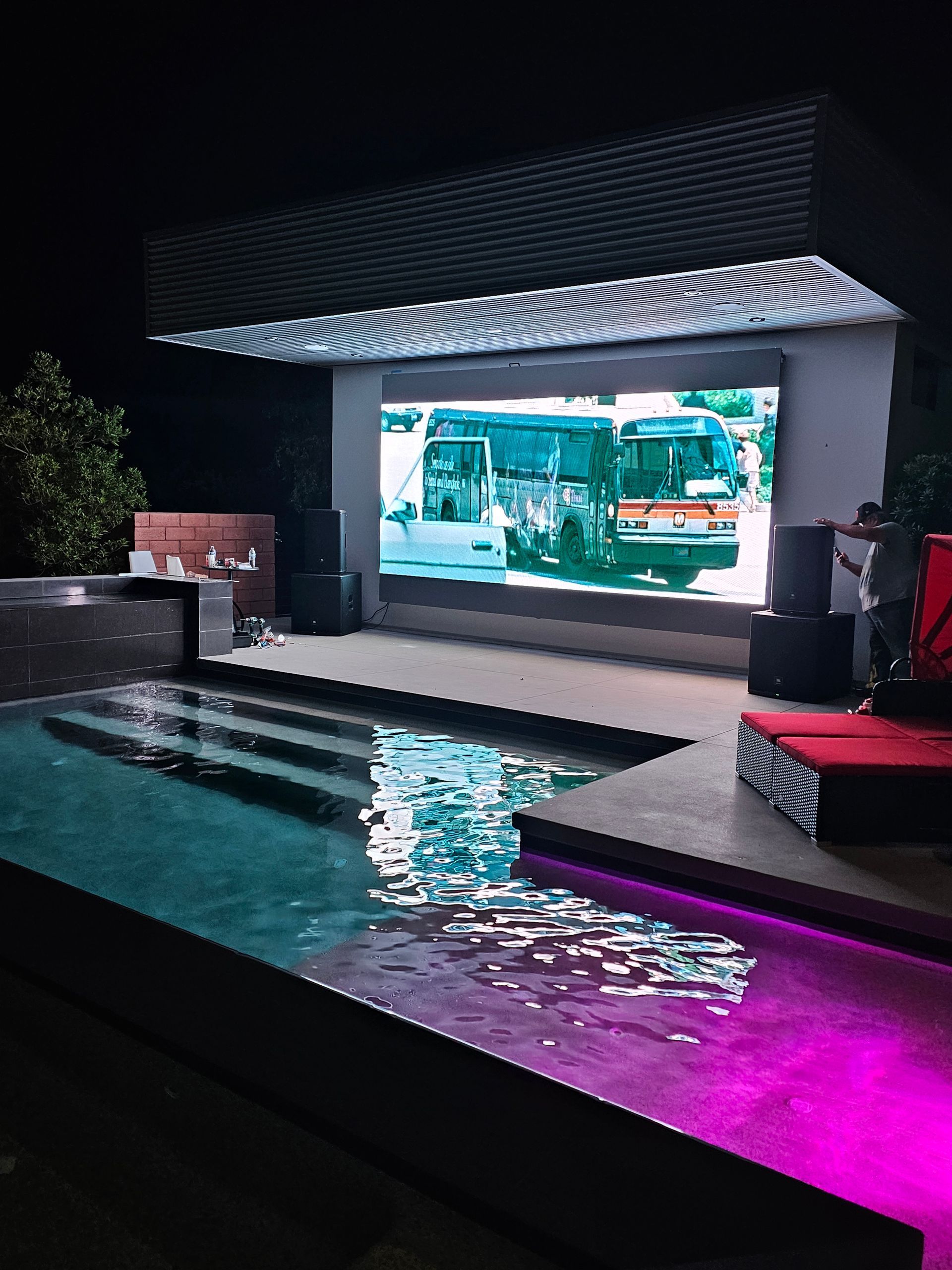 Woman in straw hat smiles, holding wine glass near a lake.