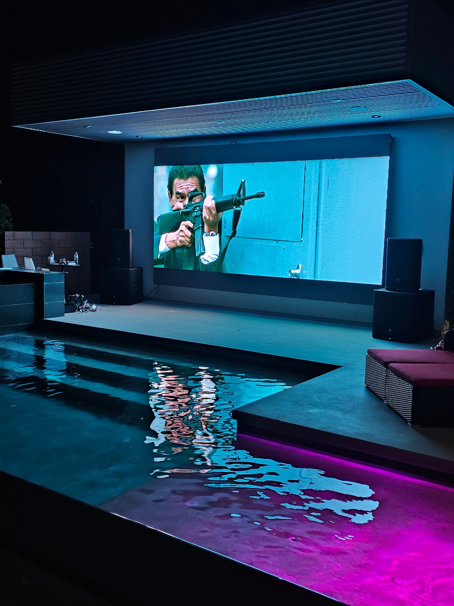 Woman in straw hat smiles, holding wine glass near a lake.