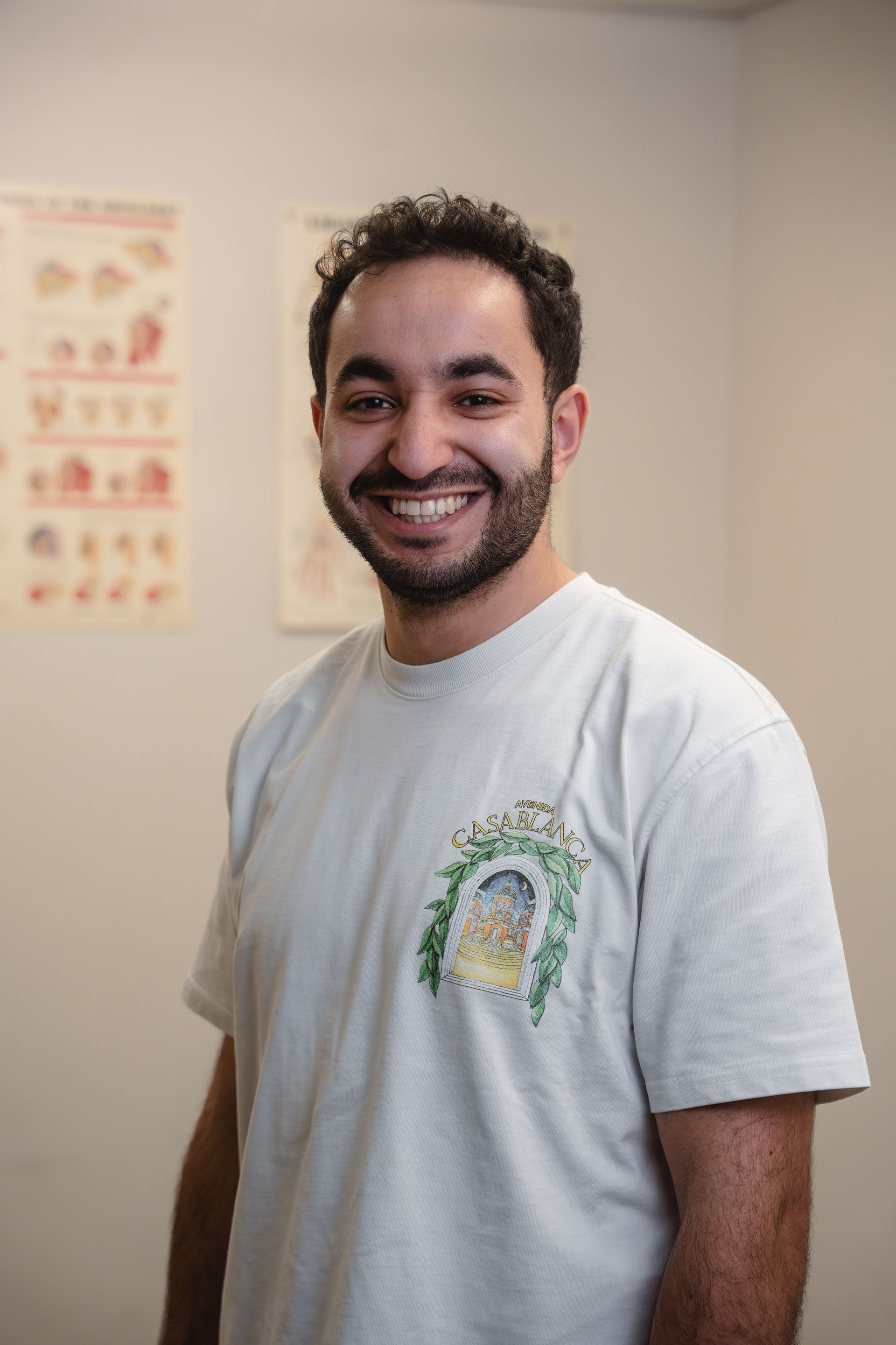 Lachende man in wit T-shirt staat bij medische dossiers.