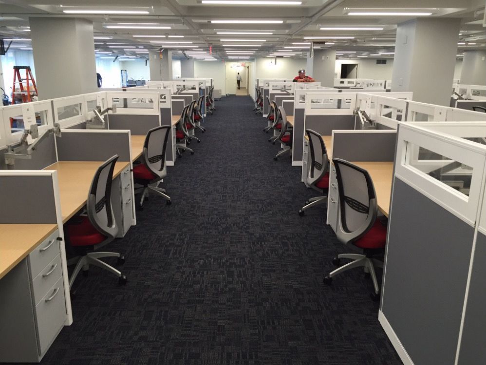 A long hallway with cubicles and chairs in an office