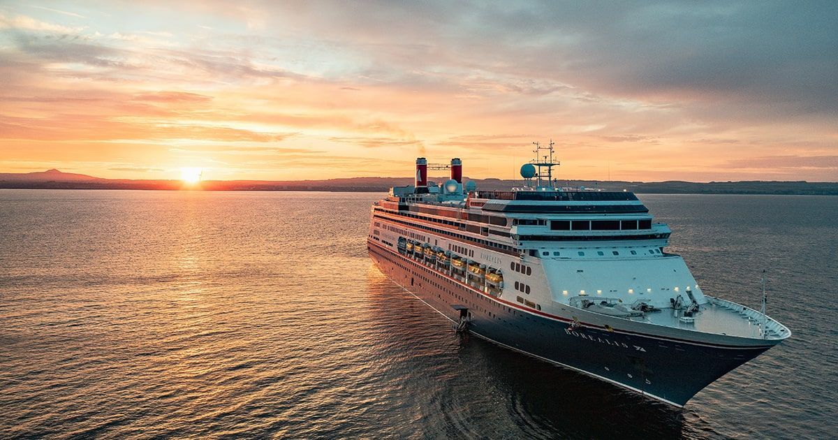 A large cruise ship is floating on top of a body of water at sunset.