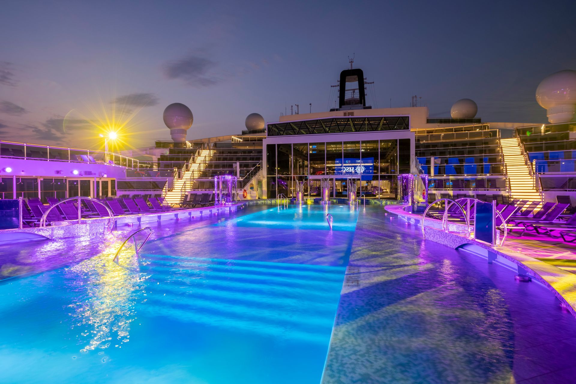 A large swimming pool on the deck of a cruise ship at night.