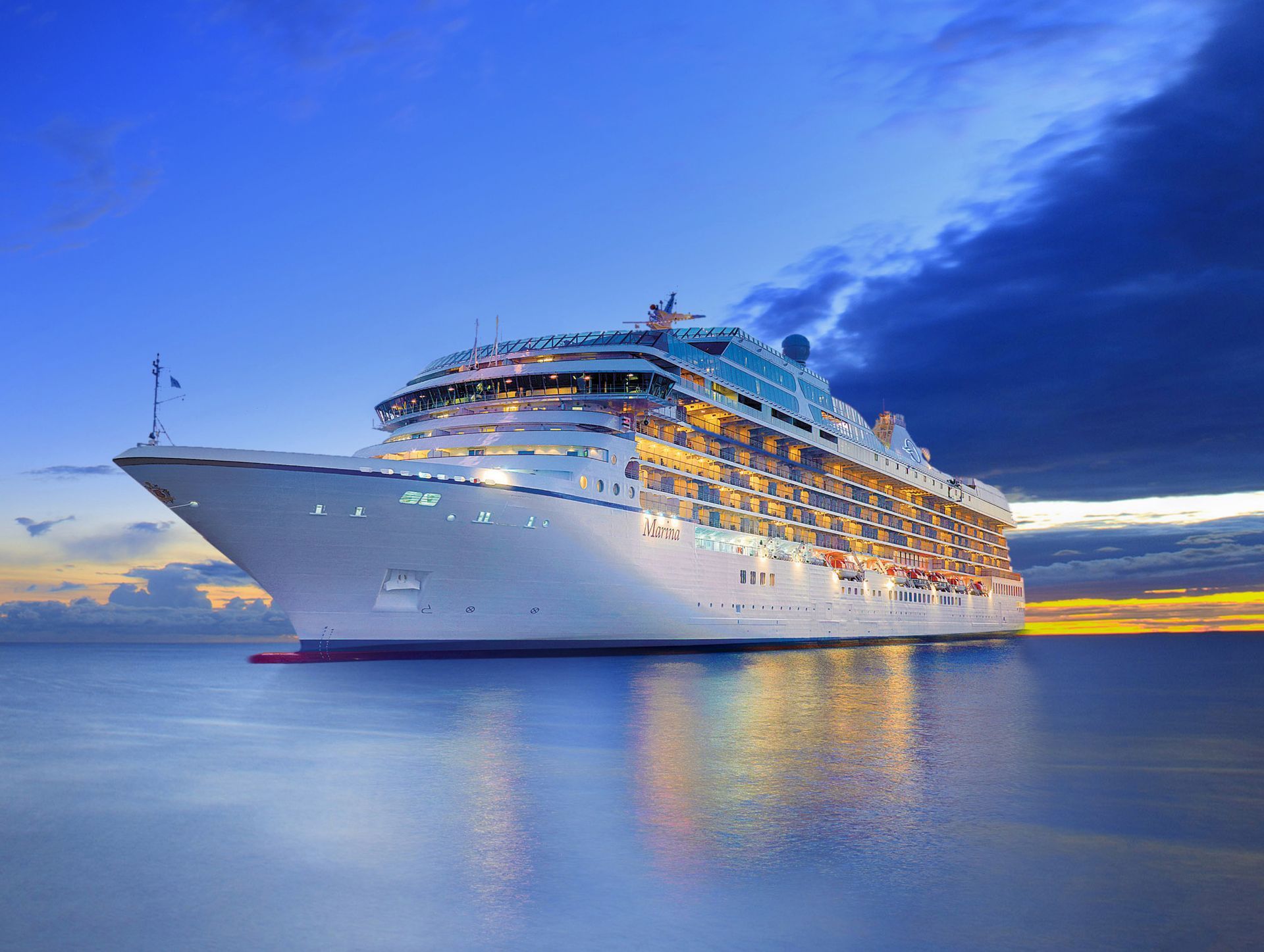 A large cruise ship is docked in the ocean at sunset.