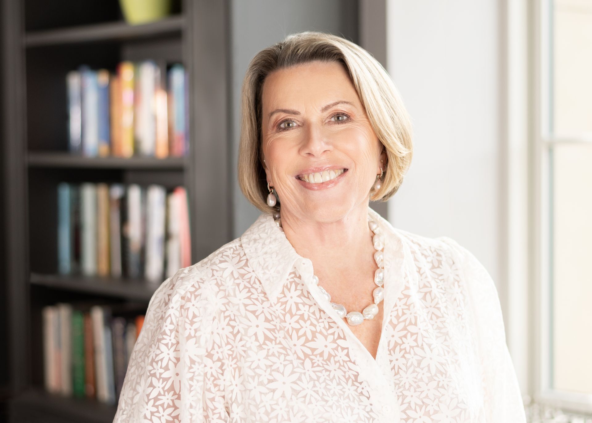A man in a yellow shirt and sunglasses is giving a peace sign on a beach.