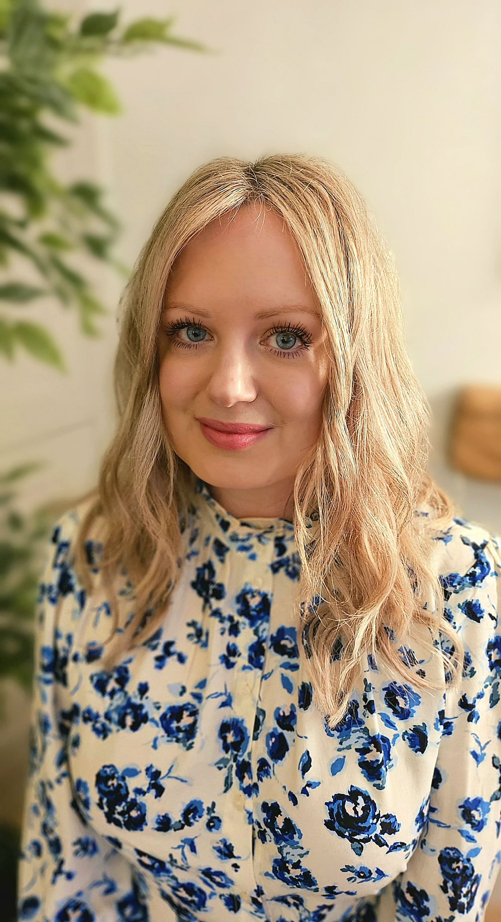 A man in a yellow shirt and sunglasses is giving a peace sign on a beach.
