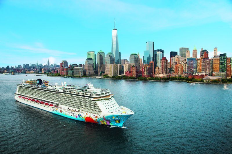 A cruise ship is floating on top of a body of water in front of a city skyline.