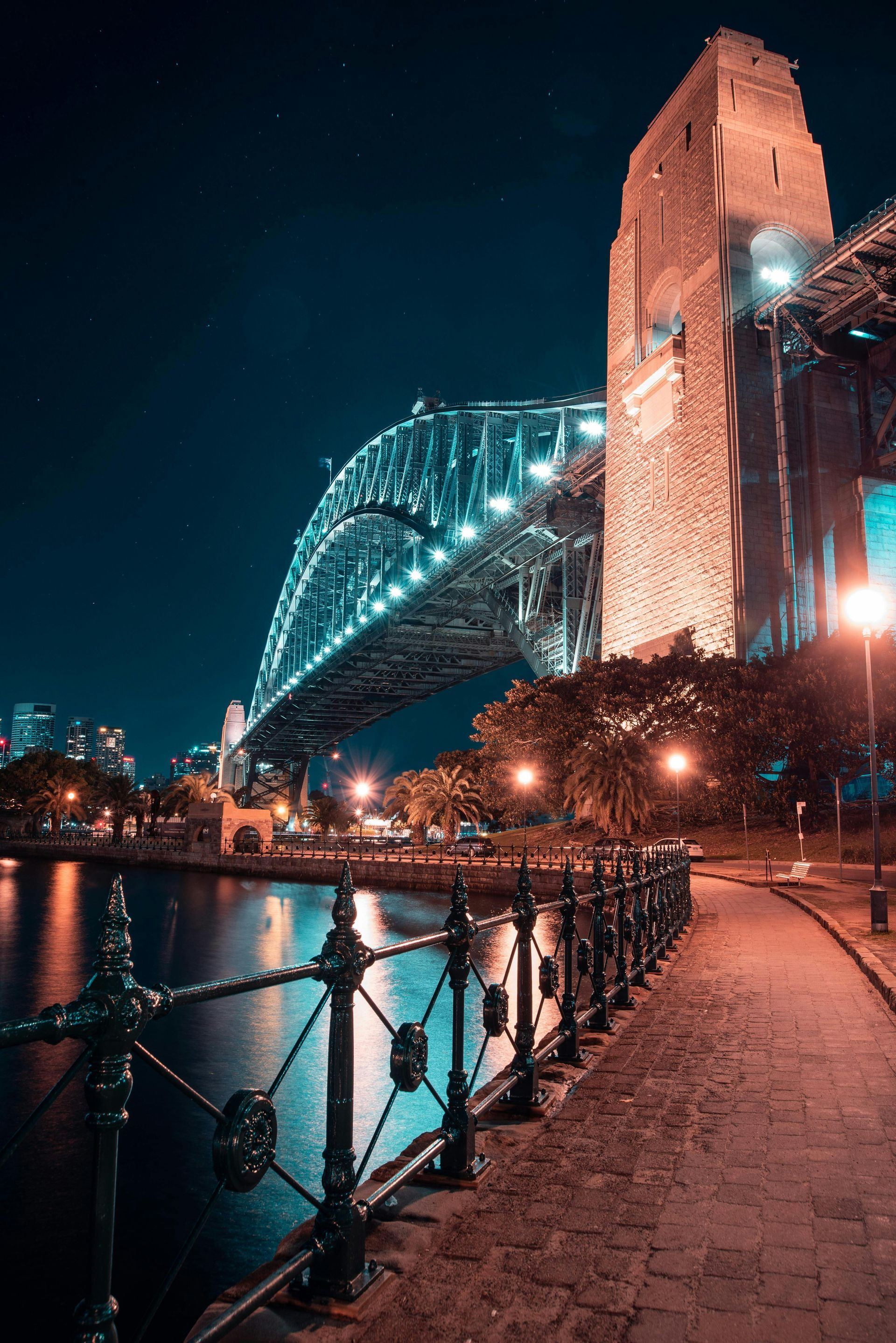 A bridge over a body of water at night with a fence in the foreground.