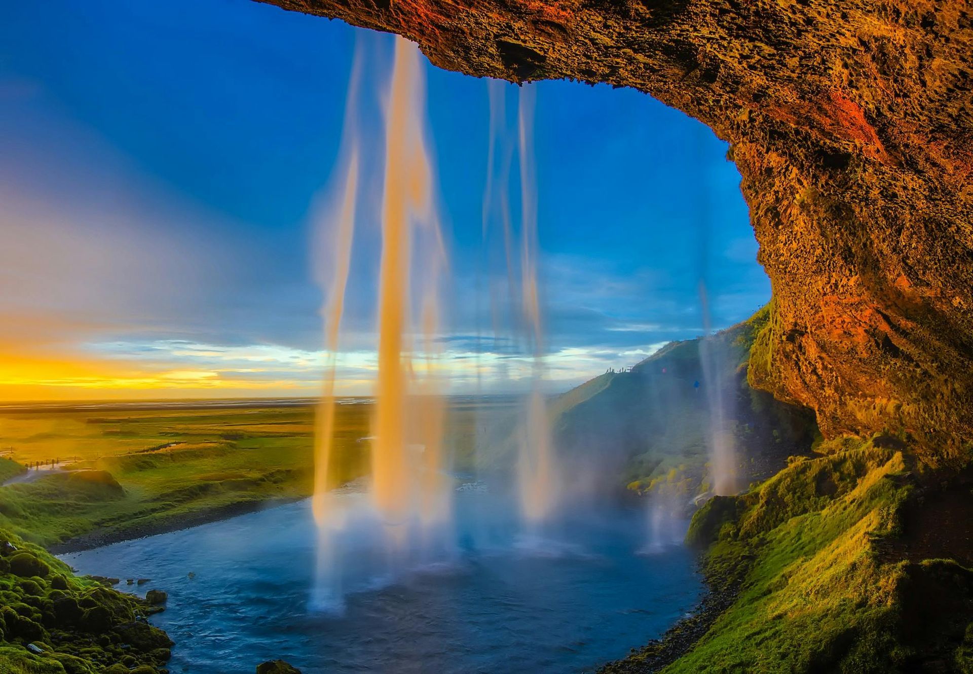 A waterfall is coming down a cliff into a river.