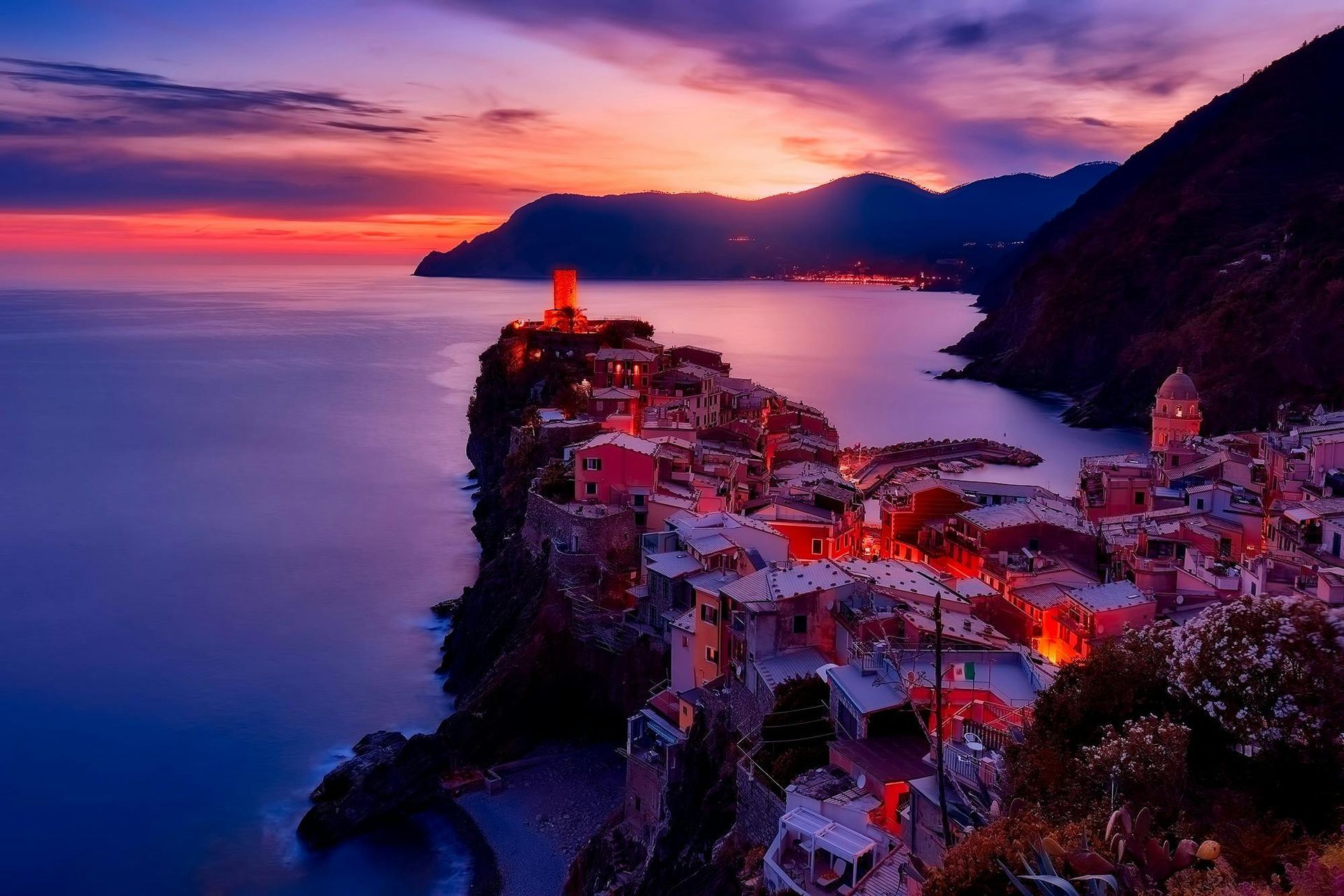 A city on a cliff overlooking the ocean at sunset