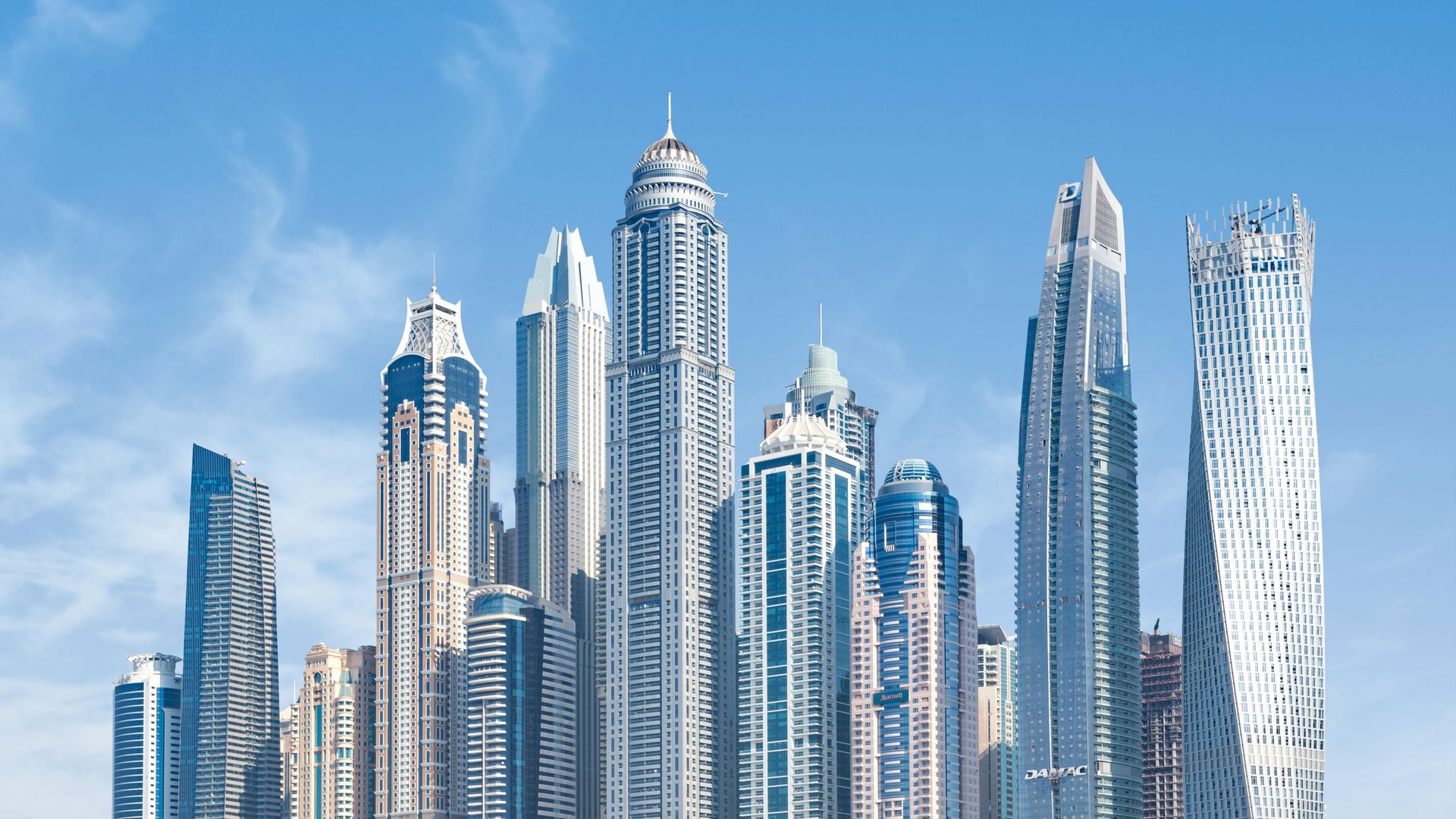 A city skyline with a lot of tall buildings against a blue sky