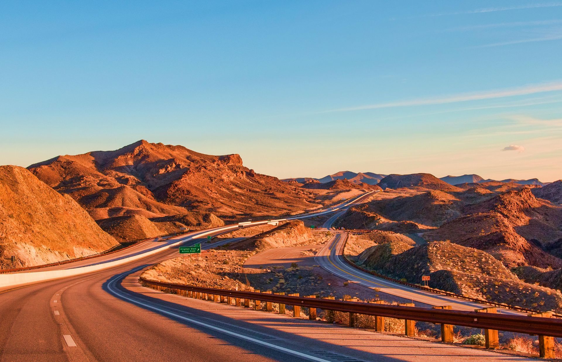 A highway going through a desert landscape with mountains in the background.