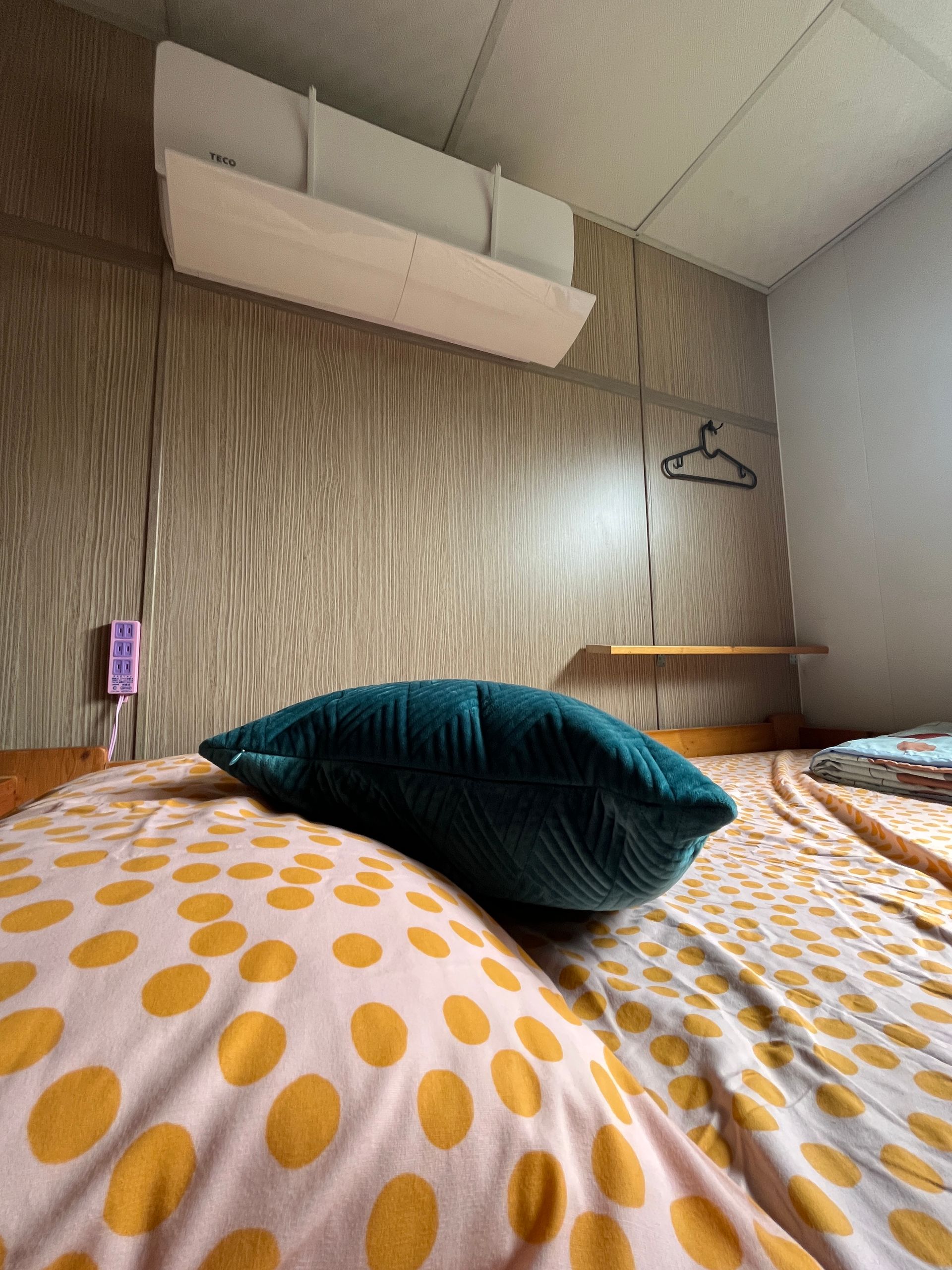 A bed with polka dot sheets and a blue pillow on it