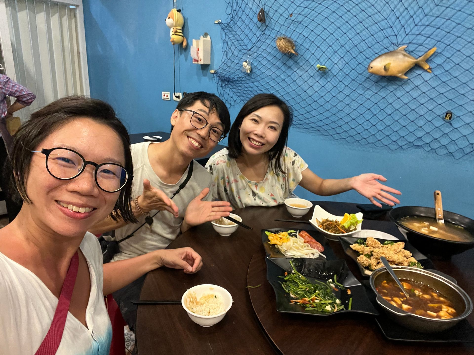 Three people are sitting at a table with plates of food.