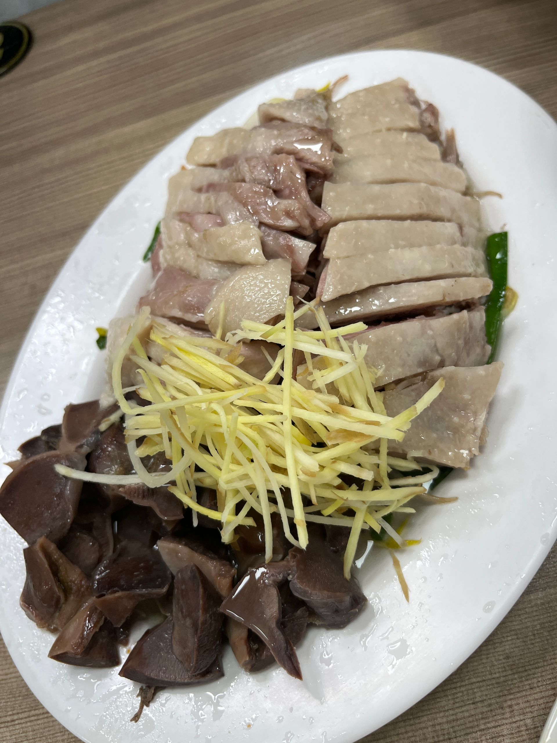 A white plate topped with meat and vegetables on a table.