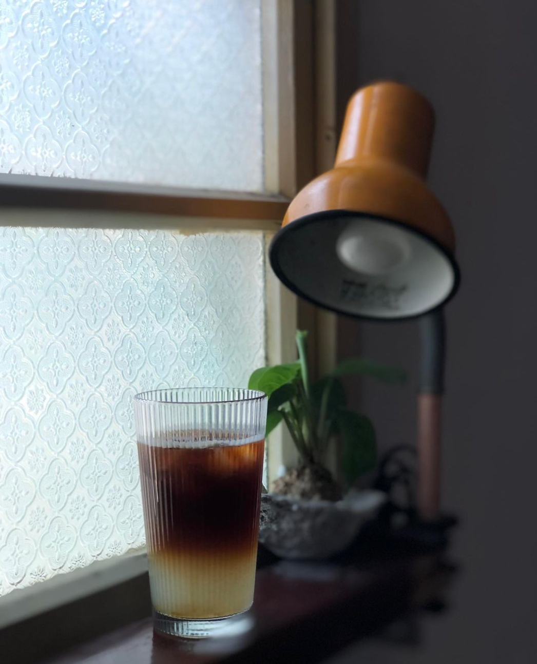 A living room with wicker chairs and a coffee table in front of a large window.