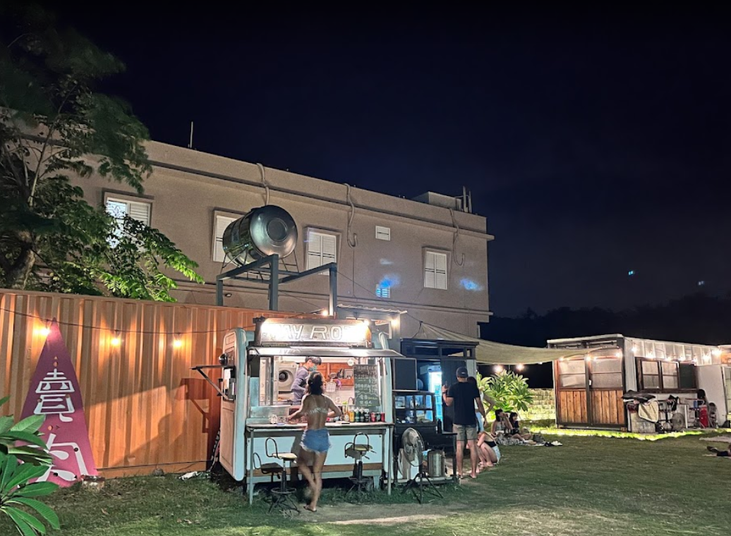 A food truck is parked in front of a building at night.