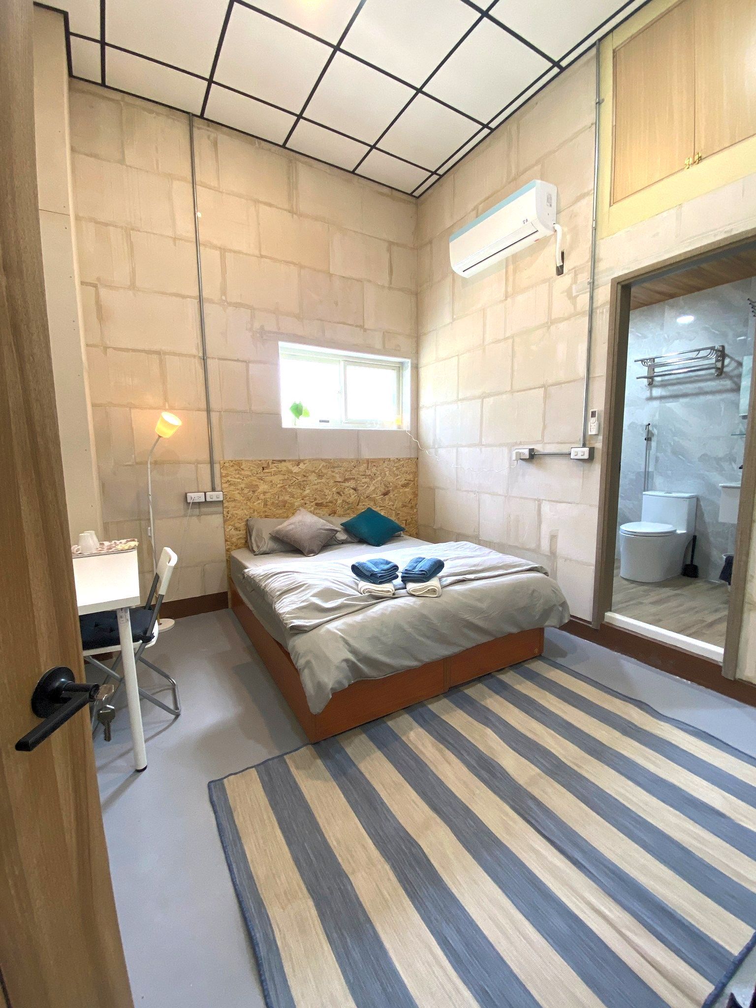 A bedroom with a bed and a striped rug.