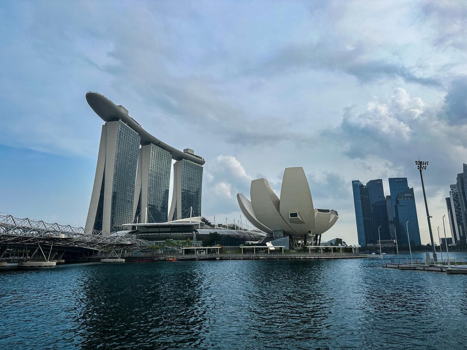 Marina Bay Sands, das ArtScience Museum und die Skyline der Stadt Singapur vor einem bewölkten Himmel über dem Wasser.